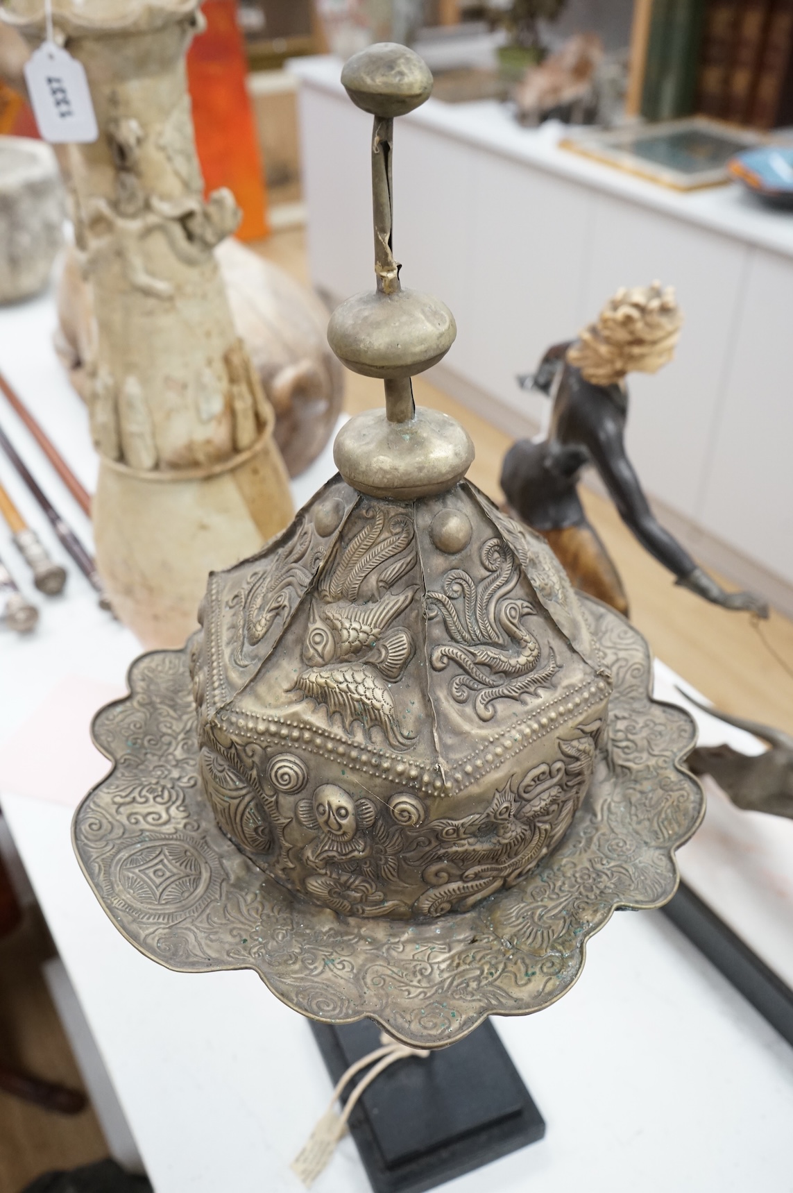 A Chinese Miao tribe embossed metal ceremonial headdress on stand, 63cm high